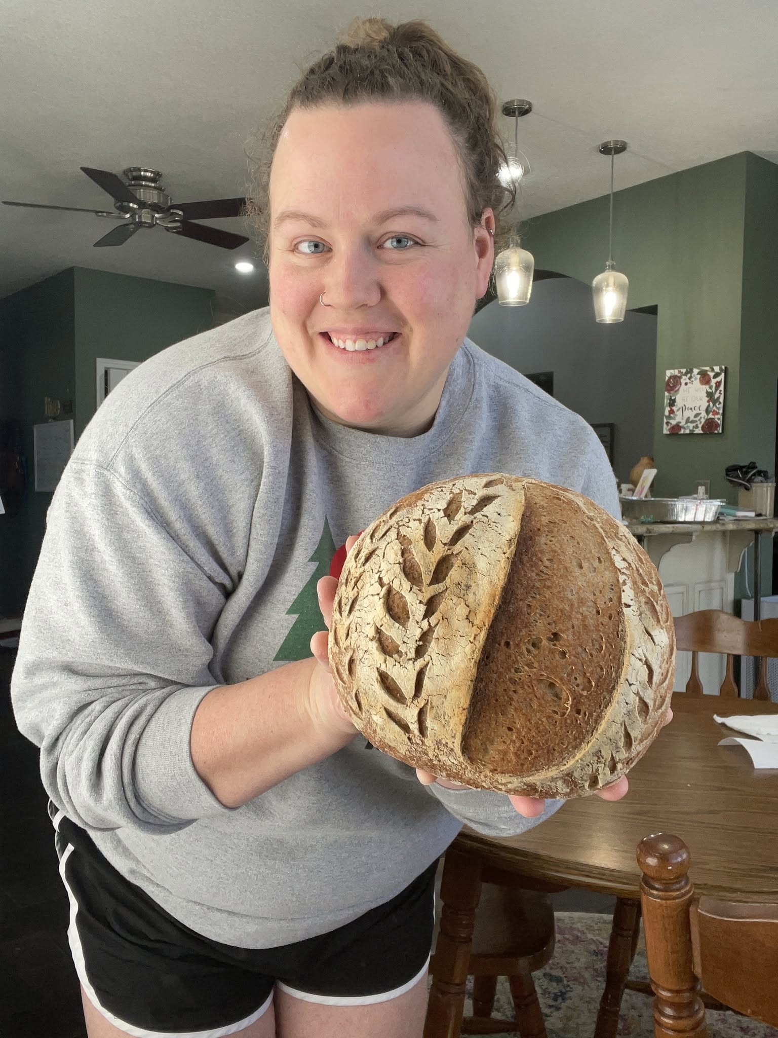 Beth holding a decorated sourdough loaf.