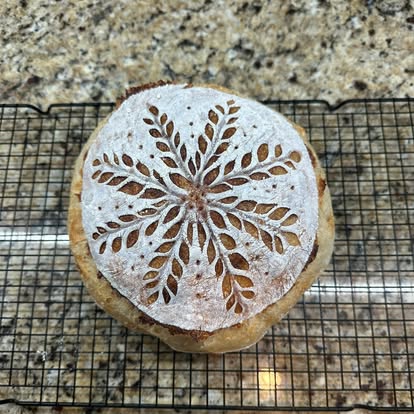 A round sourdough loaf with decorative wheat scoring.